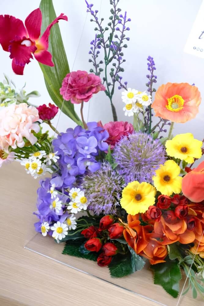 ดอกไม้ประดิษฐ์ผ้าในแจกัน  JGLORYFLOWER  แจกันพลาสติกใส รูปทรงกระเป๋า ดอกไม้คละชนิด สีม่วง/ส้ม_2