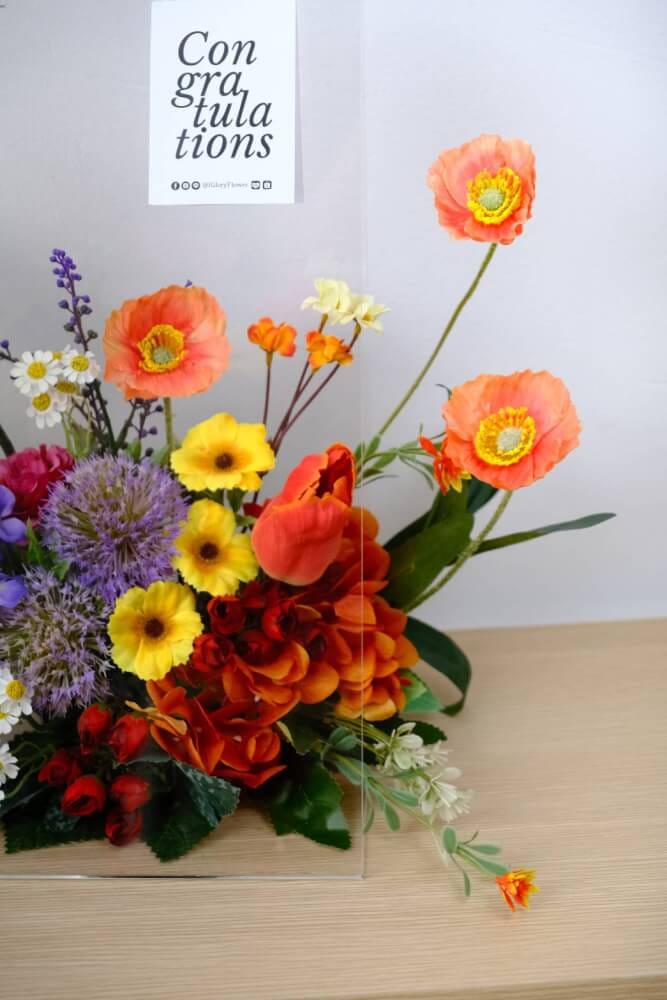 ดอกไม้ประดิษฐ์ผ้าในแจกัน  JGLORYFLOWER  แจกันพลาสติกใส รูปทรงกระเป๋า ดอกไม้คละชนิด สีม่วง/ส้ม_5